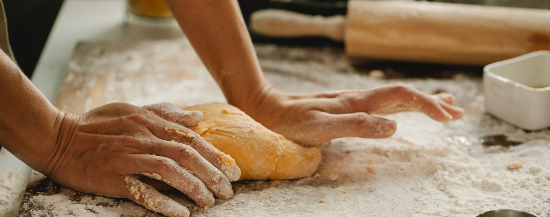 Hands kneading bread on a floured surface