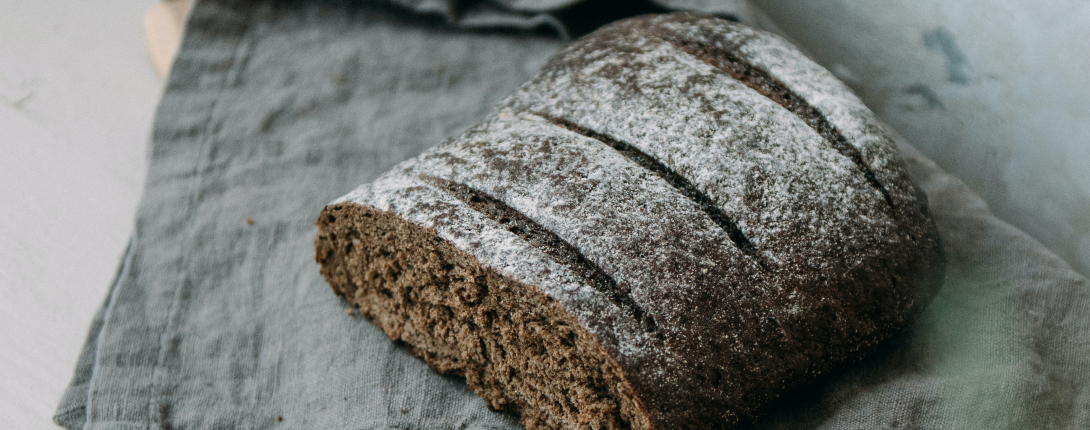 Hearty rye bread sitting on a cutting board with a knife and grey towel